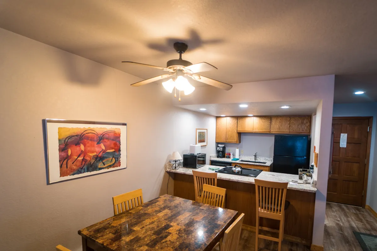 This image showcases a welcoming kitchen and dining area featuring a spacious kitchen island, a wooden dining table, and artwork on the wall. The setup encourages shared meals and gatherings, with ample space for meal prep and conversation.